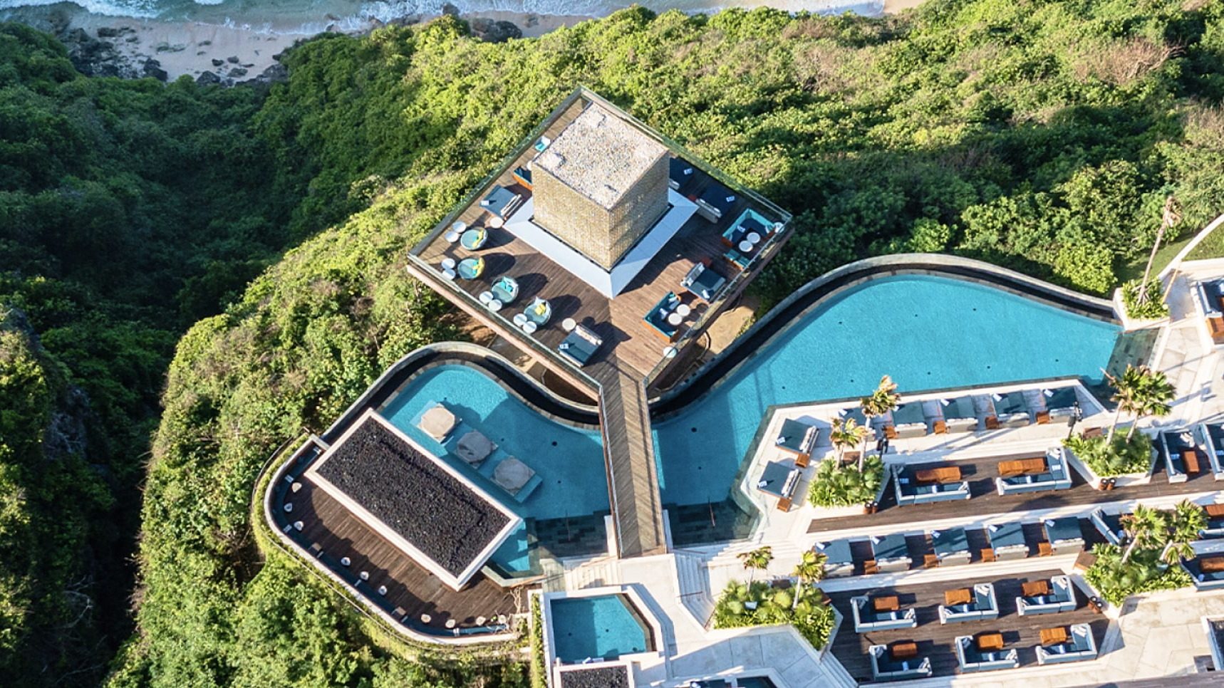 A clifftop resort with terraced pools above the sea, photographed from the air