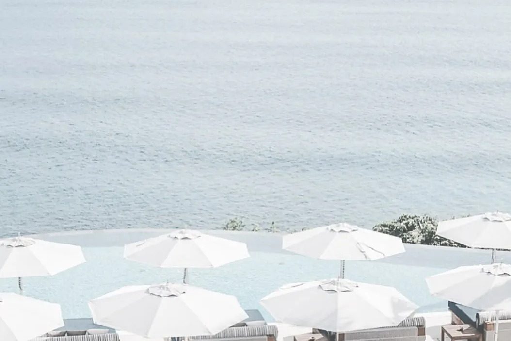 White parasols and daybeds on a beach club terrace