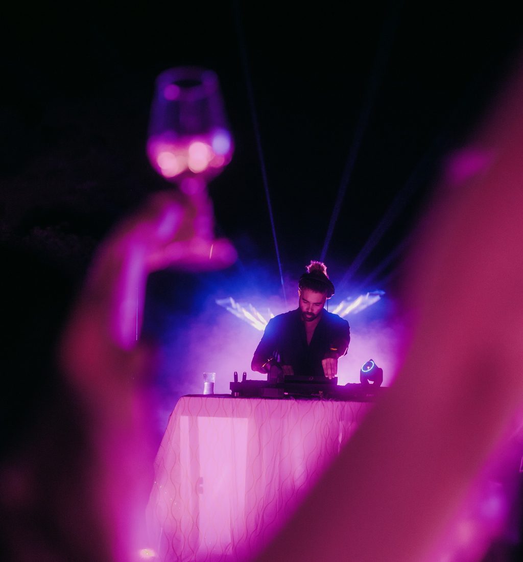 A DJ performing under magenta stage light