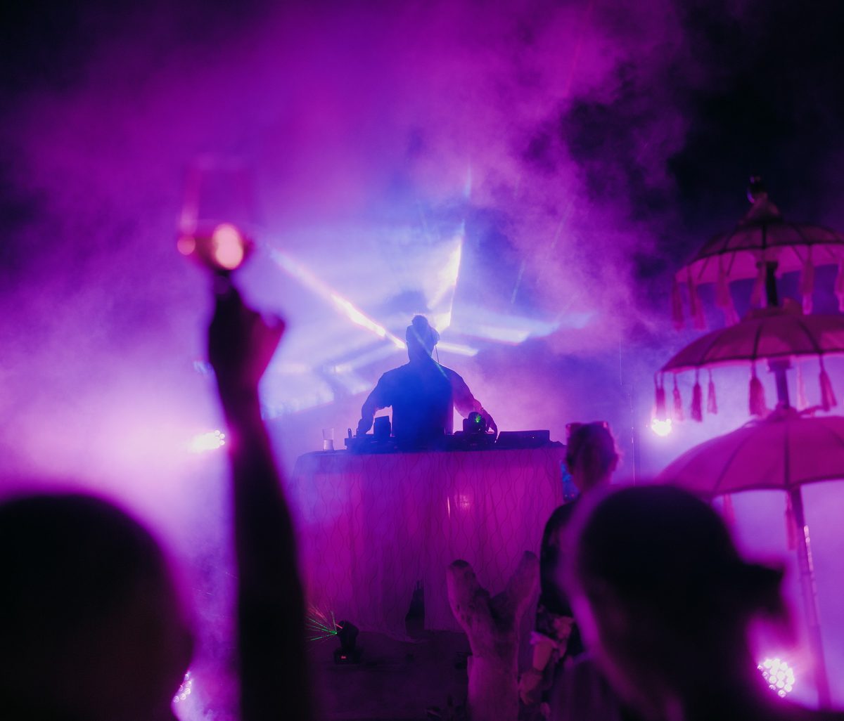 Guests dancing at a night event, lit in deep magenta