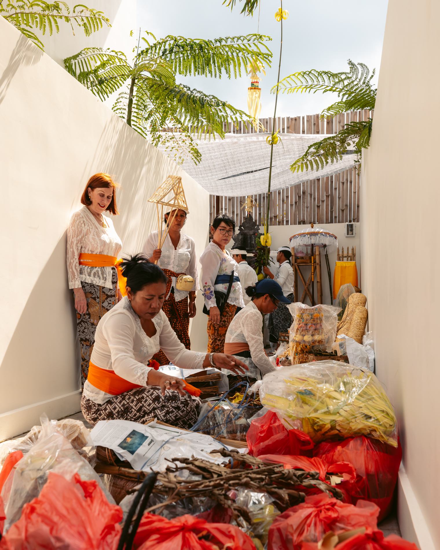 Women arranging offerings in a narrow white courtyard
