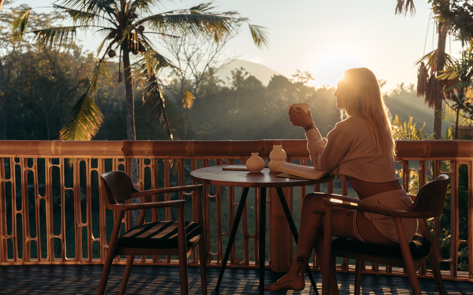 A woman with a cup of coffee on the balcony at sunset