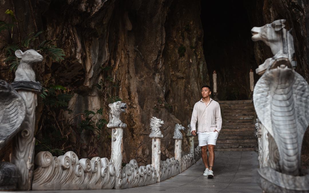 A man walking between stone animal statues at a cave temple