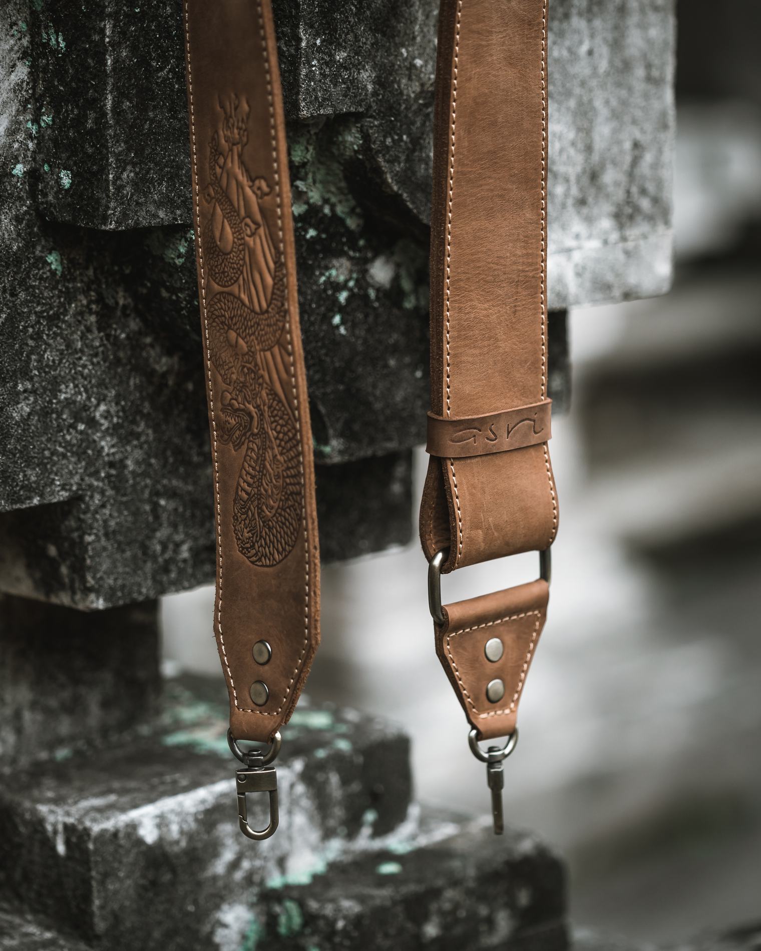Two tan straps hanging against dark stone
