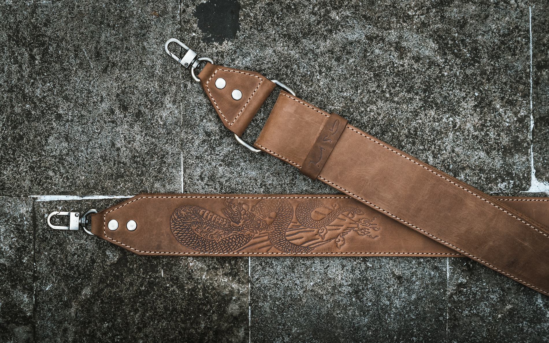 A tan strap with an embossed dragon design on a stone floor