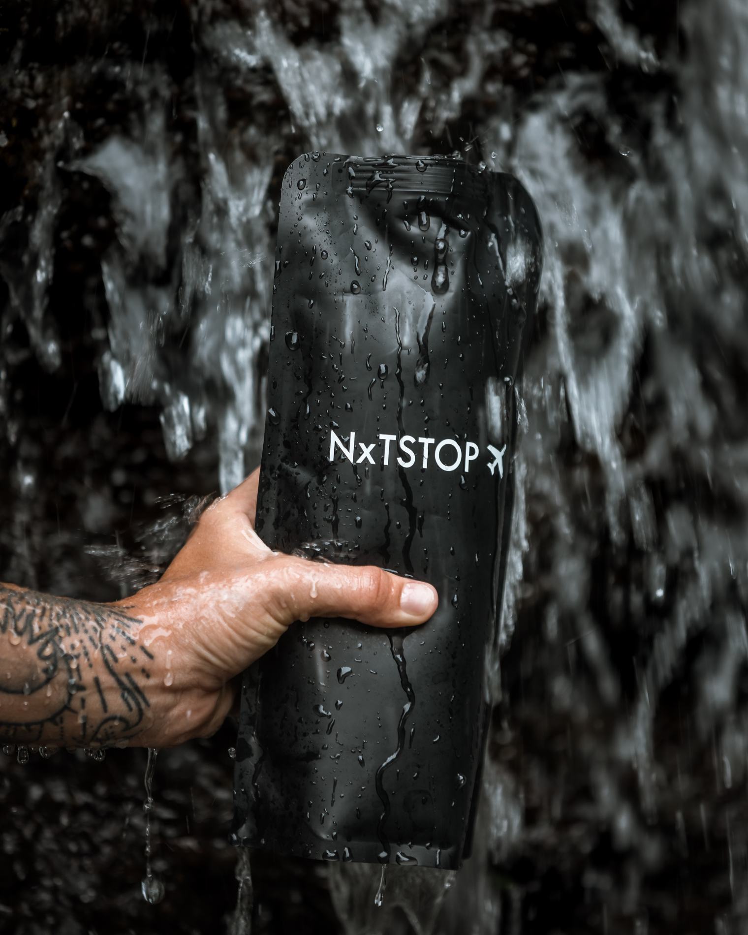 A hand holding the bottle under falling water