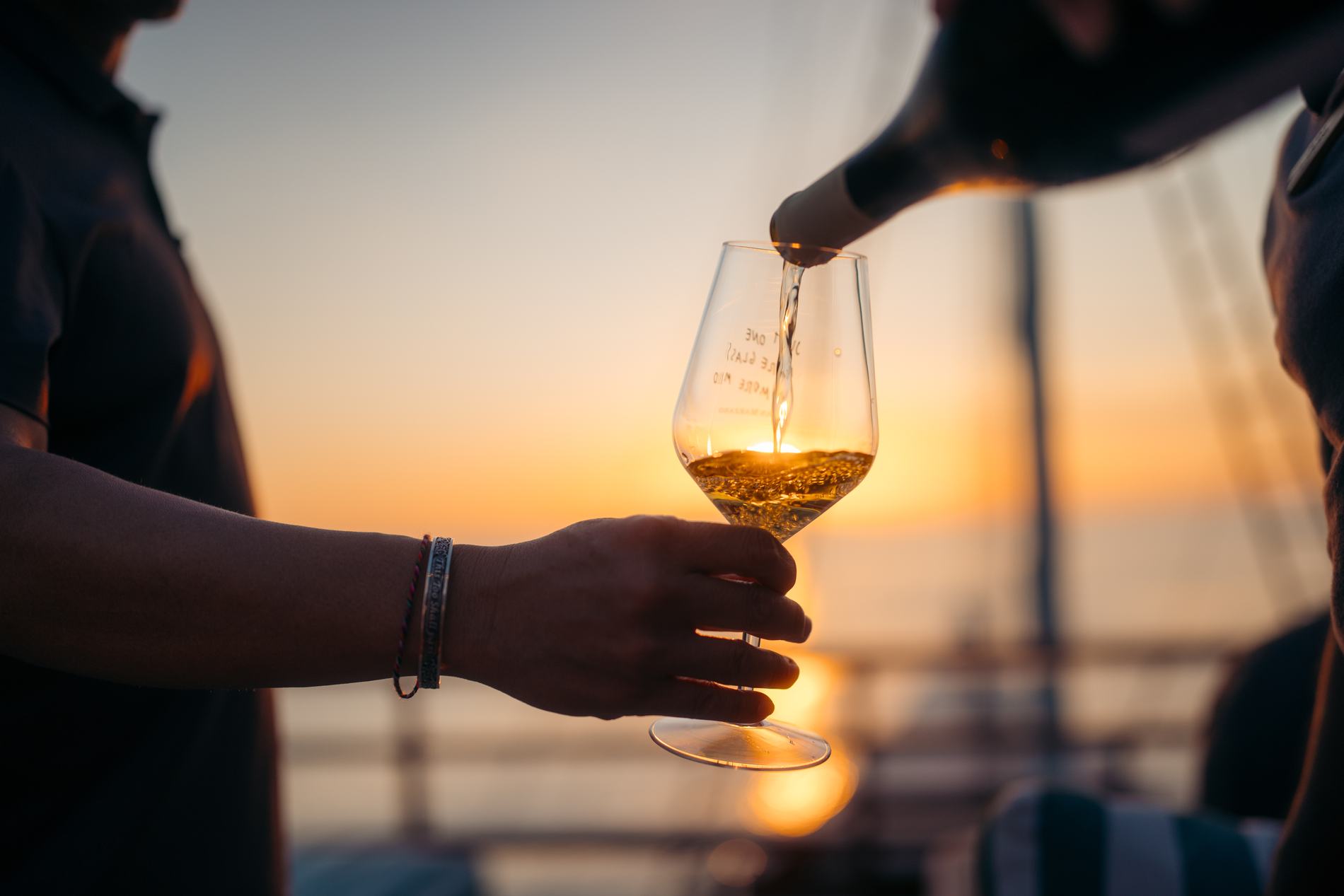 Wine being poured into a glass against the sunset