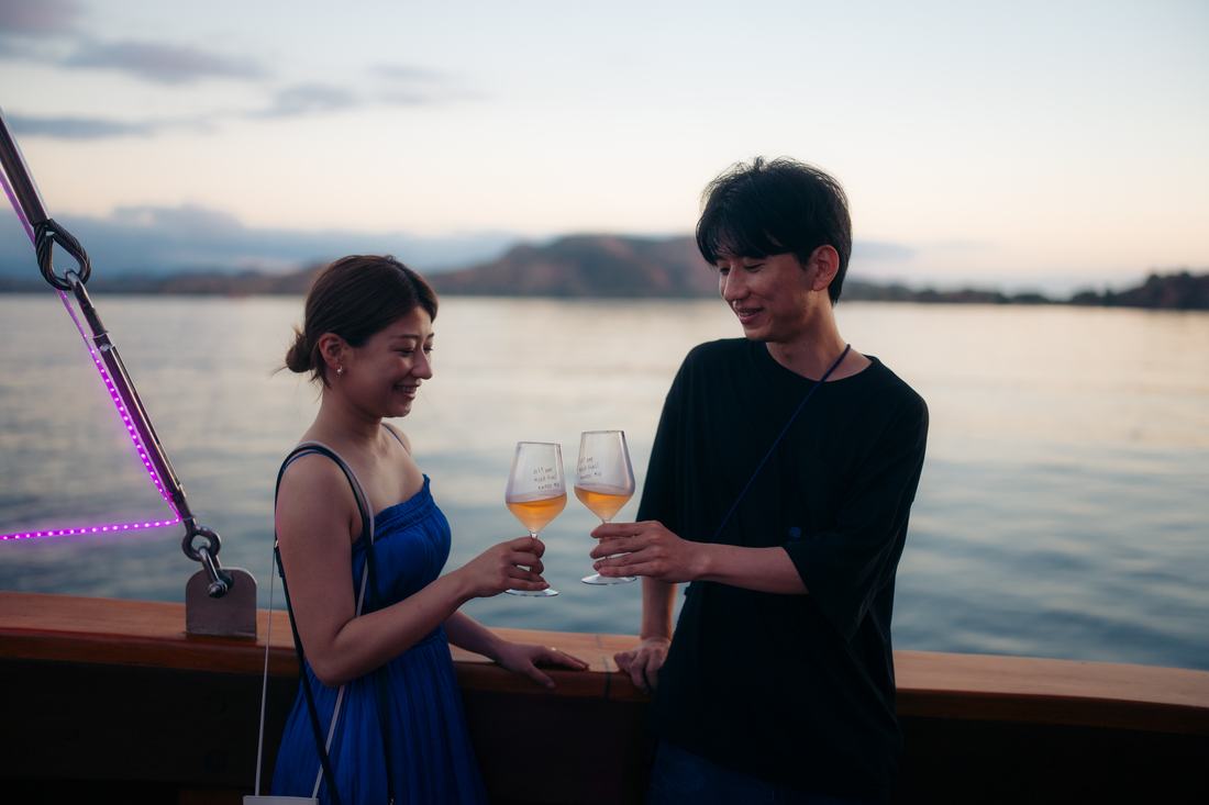 A couple toasting with glasses of wine on a ship at dusk