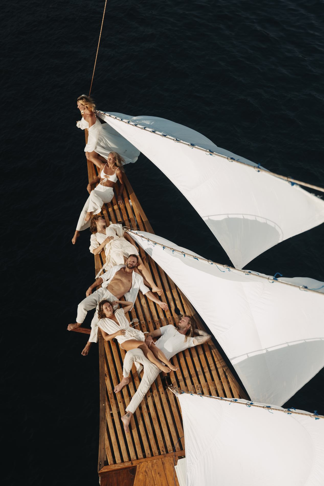 A crew in white lying along the bowsprit, seen from above