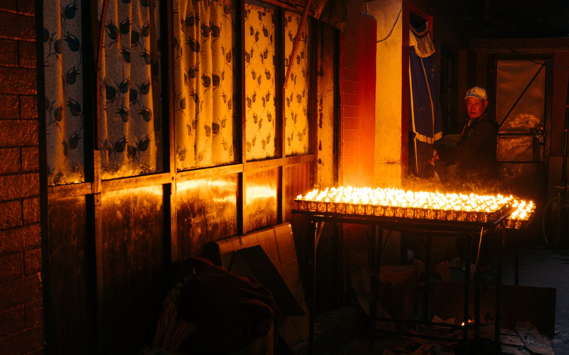 Rows of butter lamps glowing in a dark room