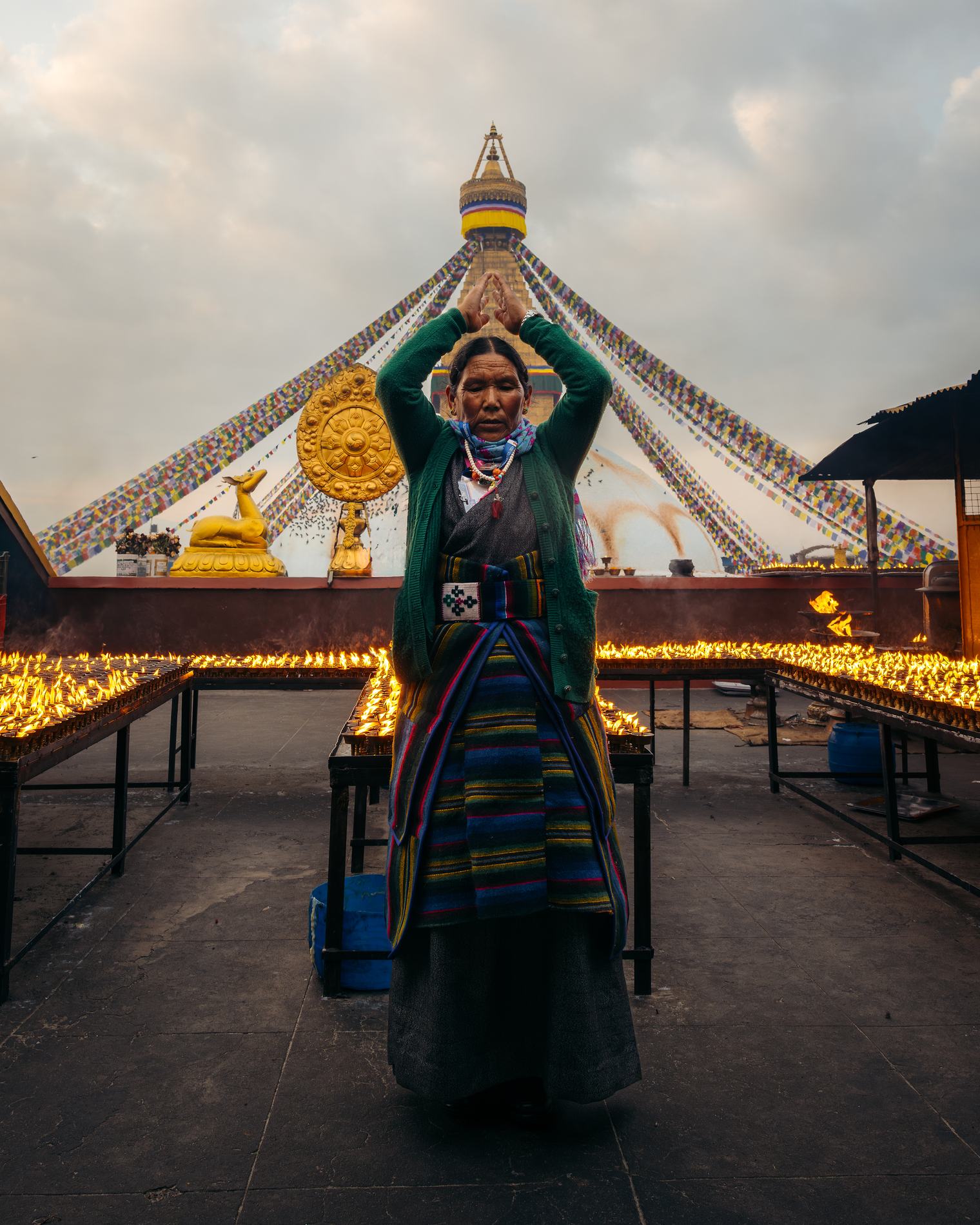 A woman with raised hands in front of the stupa at dusk