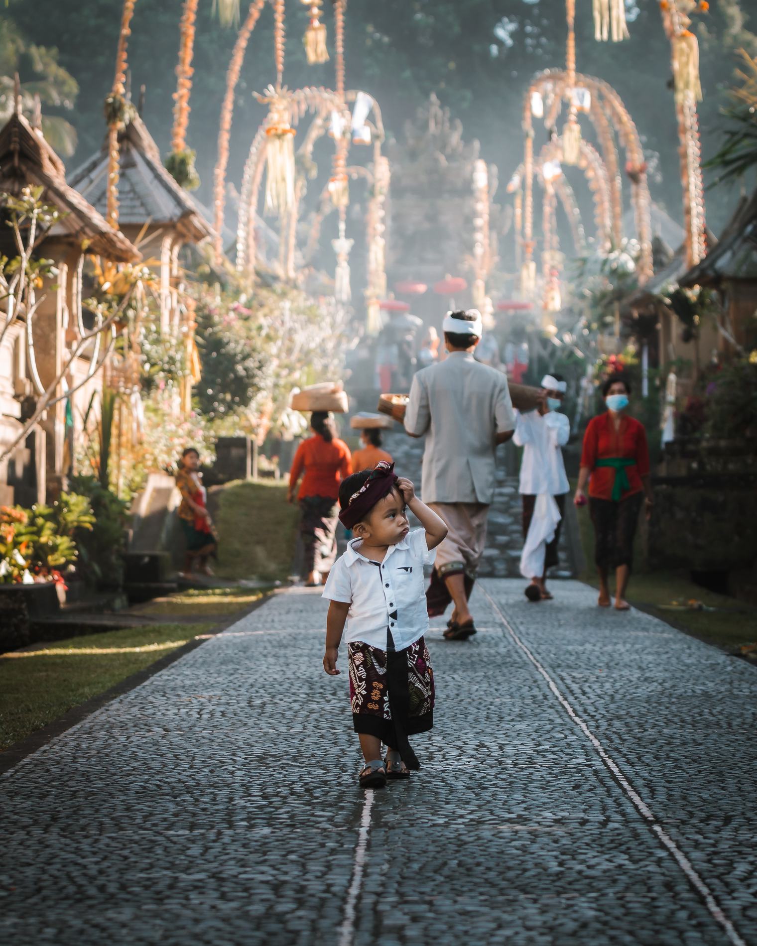 A small child walking down a cobbled village lane lined with banners
